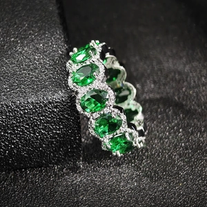 Vista macro di pietre ovali verde smeraldo su un anello eternity in argento pavé