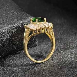 Luxury gold ring featuring emerald-cut green gemstone with radiant zircon halo setting