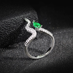 Macro shot of silver-tone snake-style ring with pavé diamonds and a pear-cut emerald green stone
