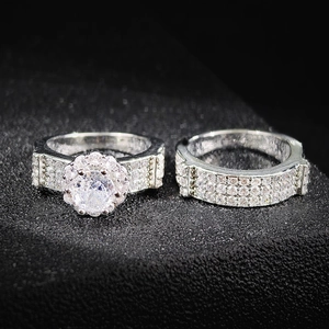Set de anillos de compromiso plateados con halo de diamantes y elegante diseño de pavé