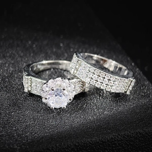 Elegante conjunto de anillos de compromiso plateados con piedra central halo y banda pavé