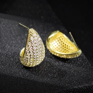 Elegant gold-tone teardrop earrings with pavé set cubic zirconia on black background