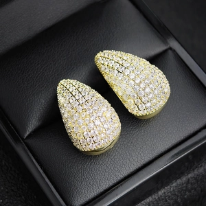 Close-up of gold teardrop earrings with pavé-set zircons on a black leather jewelry box