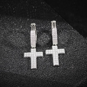 Close-up of silver cross earrings featuring micro-pave white zircon on black background