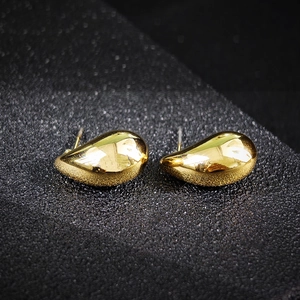 Elegante goldene Tropfenohrringe mit poliertem Spiegelglanz auf dunklem Hintergrund