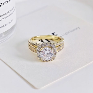 Elegante anillo chapado en oro con gran circonita central y banda de pavé de tres hileras