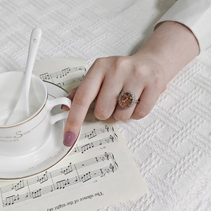 Elegant oval champagne gemstone ring with zircon halo worn in a vintage lifestyle setting