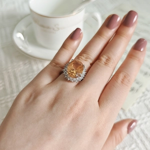 Luxury champagne gold oval zircon ring with halo diamond setting on model's hand