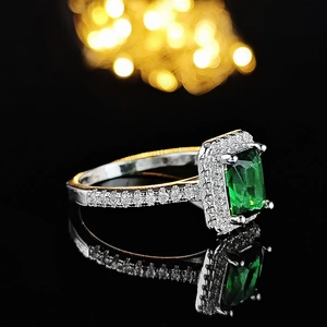 Eleganter quadratischer smaragdgrüner Ring mit Diamant-Halo auf schwarzem Hintergrund