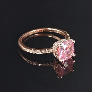 Macro shot of rose gold ring with a large square pink gemstone and halo diamond setting