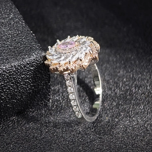 Anillo en forma de flor con circón rosa y pétalos blancos en joyero de cuero negro