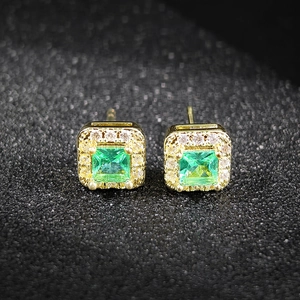 Detalle macro de pendientes de esmeralda cuadrada con halo de circonitas blancas brillantes