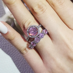 Close-up of pink zircon ring set featuring a halo solitaire and a five-stone band