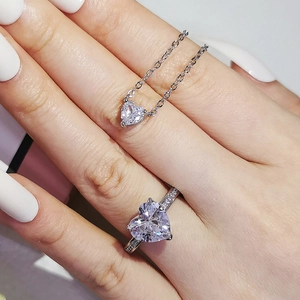 Elegant heart-shaped gemstone jewelry set including necklace and ring on model's hand