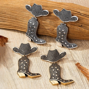 Detail of vintage cowboy boot earrings with star engraving in gold and silver finish