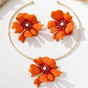 Close-up of orange floral jewelry set with golden edges and white pearl center