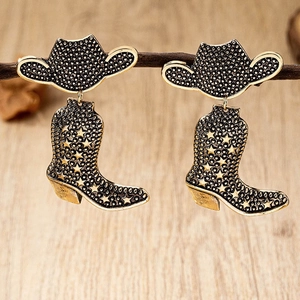 Detail of vintage cowboy boot and hat drop earrings with star motif on branch