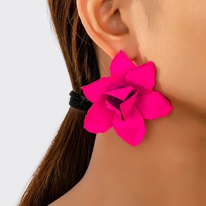 Close-up of a model wearing large matte rose red layered flower geometric earrings