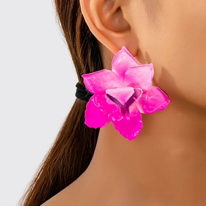 Side view of model wearing oversized matte fuchsia orchid earrings in bold floral design