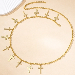 Detailed macro view of golden metal body chain with textured cross pendants and lobster clasp