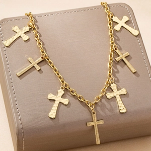 Golden cross pendant body chain on leather box featuring hammered and linear textures