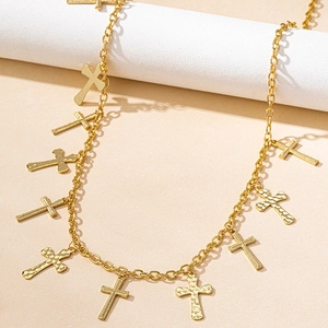 Detailed macro view of golden cross charms with hammered textures on a beach waist chain