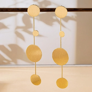 Detail of oversized gold geometric flower earrings with brushed matte finish on large discs