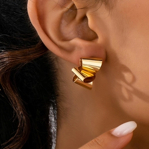 Poliertes Gold geometrische gedrehte Ohrringe getragen von Model im Nahaufnahme-Stil