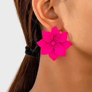 Detail of vibrant magenta floral earrings with matte petals on a model's ear
