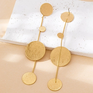 Detailed macro view of triple brushed gold geometric discs on elegant metal earrings