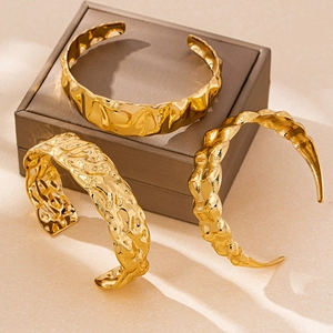Détails de trois bracelets dorés aux textures irrégulières sur un coffret à bijoux
