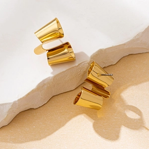 Detail von gedrehten geometrischen Goldohrringen mit Spiegelglanz auf Steinsockel