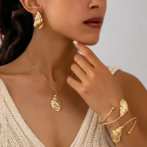 Elegante conjunto de joyas doradas con collar en espiral, pendientes y pulsera en modelo