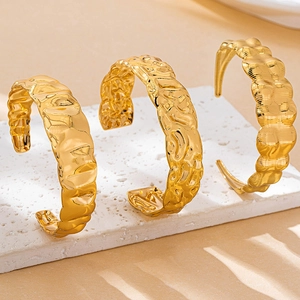 Détail de trois bracelets dorés ouverts avec texture martelée sur support en pierre