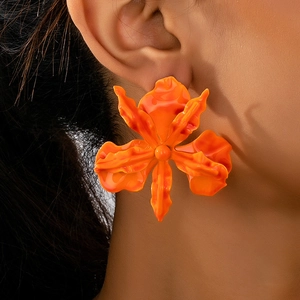 Close-up of oversized orange flower earrings with glossy finish on female model