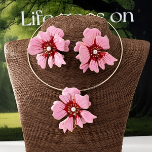 Detail of pink enamel flower jewelry set with beaded center and gold choker necklace
