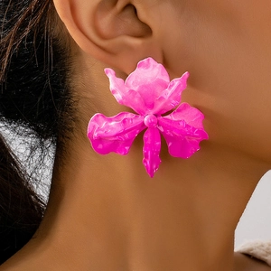Detailed close-up of oversized neon pink orchid flower earrings with matte lacquer finish