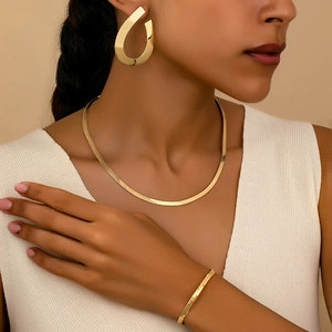 Golden geometric jewelry set featuring teardrop earrings, snake chain, and open cuff bracelet