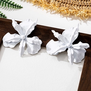 Macro detail of large white floral earrings with wavy petals and matte lacquer finish
