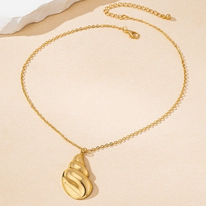 Detalle de collar dorado con colgante de caracola pulida y cierre de langosta ajustable