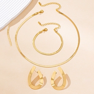 Detail of gold geometric jewelry set featuring flat snake chain and water drop earrings