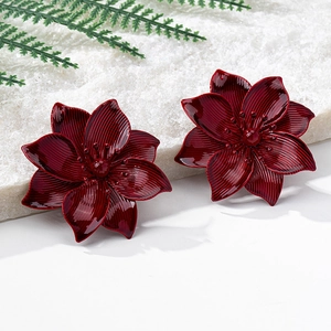 Detail of red flower stud earrings with radial texture on a marble stone surface