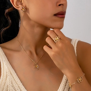 Detalle de conjunto de joyas florales doradas con piedras amarillas en modelo con collar