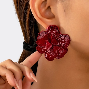 Statement burgundy floral earring with textured metallic finish on model in a close-up view