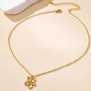 Detalle del collar dorado con colgante de flor de cinco pétalos y una piedra preciosa amarilla