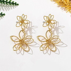 Detail showing oversized golden double floral earrings with intricate hollow wire design