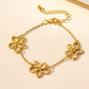 Detalle de pulsera dorada con flores caladas y cristales de color ámbar brillante