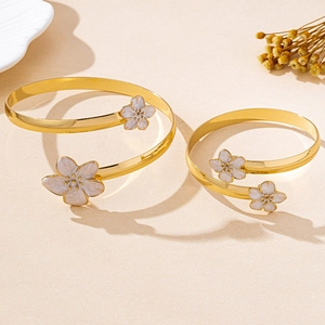 Gros plan de bracelets spirales dorés avec détails de fleurs de cerisier en émail blanc