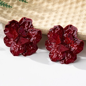 Detailed view of vintage dark red floral earrings with layered glossy petals on ceramic