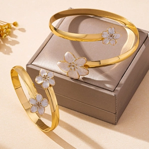 Détail d'un bracelet ouvert doré avec pétales de cerisier en émail blanc et texture dorée